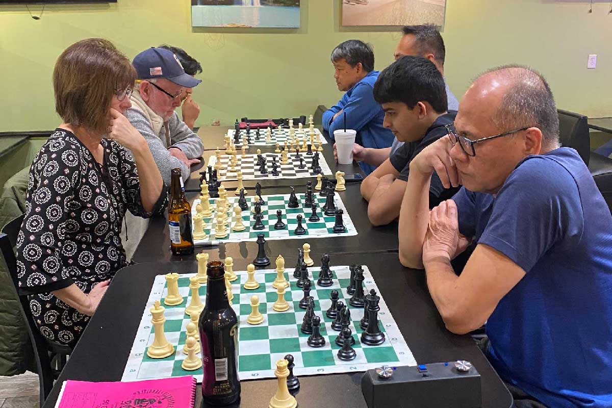 A woman and six men playing chess