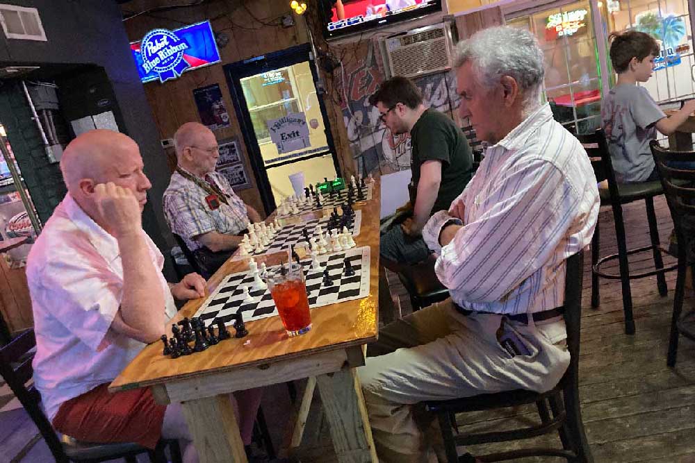 Four older men playing chess
