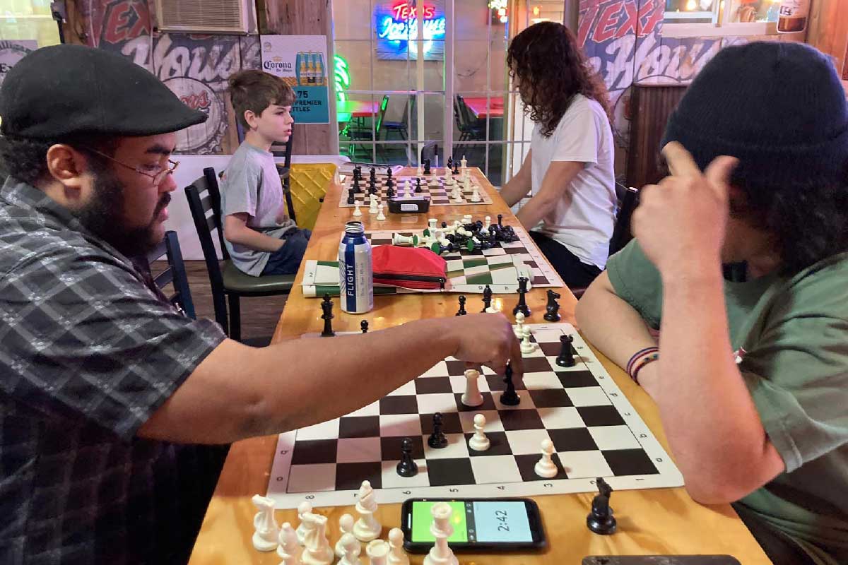 Four young men playing chess at J. Gilligan's